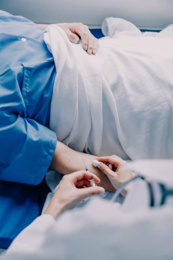 Hastanede koğuşta yatakta Asyalı kadın hasta muayene çeşitli doktorların yan görünümü.