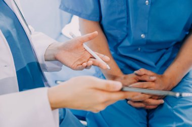 Hastanede koğuşta yatakta Asyalı kadın hasta muayene çeşitli doktorların yan görünümü.