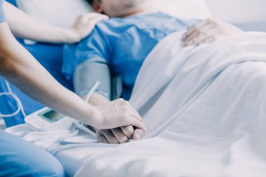 Hastanede koğuşta yatakta Asyalı kadın hasta muayene çeşitli doktorların yan görünümü.