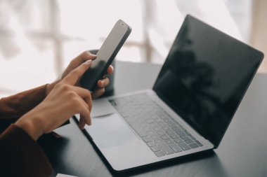 Çekici gülümseyen Asyalı iş kadını ev ofisinde çalışıyor, Asyalı kadın dizüstü bilgisayarında tablet tutuyor..