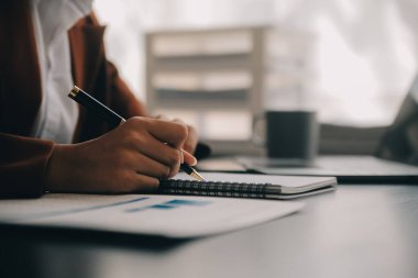 Çekici gülümseyen Asyalı iş kadını ev ofisinde çalışıyor, Asyalı kadın dizüstü bilgisayarında tablet tutuyor..