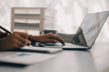 Çekici gülümseyen Asyalı iş kadını ev ofisinde çalışıyor, Asyalı kadın dizüstü bilgisayarında tablet tutuyor..