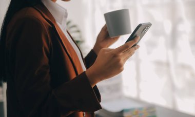 Çekici gülümseyen Asyalı iş kadını ev ofisinde çalışıyor, Asyalı kadın dizüstü bilgisayarında tablet tutuyor..