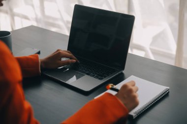 Çekici gülümseyen Asyalı iş kadını ev ofisinde çalışıyor, Asyalı kadın dizüstü bilgisayarında tablet tutuyor..
