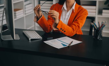 Çekici gülümseyen Asyalı iş kadını ev ofisinde çalışıyor, Asyalı kadın dizüstü bilgisayarında tablet tutuyor..