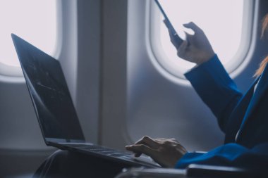 Cep telefonu ve dizüstü bilgisayar kullanan düşünceli Asyalı kadın yolcu gemisi, uçak penceresi tatil seyahatinin heyecanını ve heyecanını mükemmel bir şekilde yakalıyor. Çinliler, Japonlar..