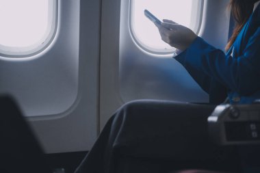 Cep telefonu ve dizüstü bilgisayar kullanan düşünceli Asyalı kadın yolcu gemisi, uçak penceresi tatil seyahatinin heyecanını ve heyecanını mükemmel bir şekilde yakalıyor. Çinliler, Japonlar..