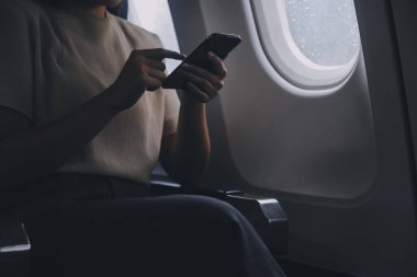 Çekici Asyalı kadın uçak yolcusu dizüstü bilgisayar ve tabletle kablosuz bağlantı kullanarak rahat koltukta oturuyor. Stil içinde seyahat et, zarafetle çalış..