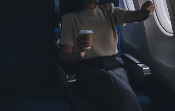 アジアの女性は 飛行機のキャビンに座っている間 コーヒー快適な飛行を楽しんでいます 窓の近くの乗客 — ストック写真