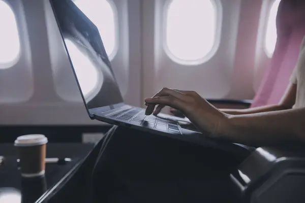 窓の近くに飛行機に座って ソーシャルネットワークからニュースを読んだり スマートフォンで旅行アプリケーションを使用するアジアの女性の乗客 — ストック写真
