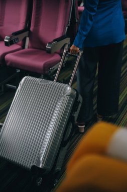 Asyalı bayan gezgin uçağa binerken bavullarını üst kattaki dolaba koyuyor..