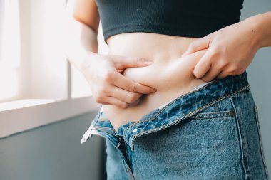 Şişman kadın, şişko, obez kadın el ele tutuşan ölçü bandıyla göbek yağı, kadın diyeti yaşam tarzı konsepti