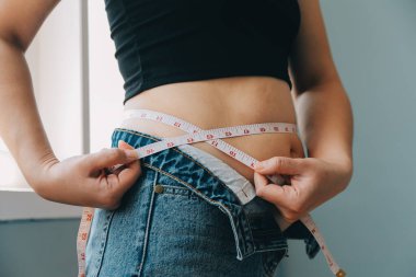 Şişman kadın, şişko, obez kadın el ele tutuşan ölçü bandıyla göbek yağı, kadın diyeti yaşam tarzı konsepti