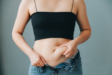 Şişman kadın, şişko, obez kadın el ele tutuşan ölçü bandıyla göbek yağı, kadın diyeti yaşam tarzı konsepti