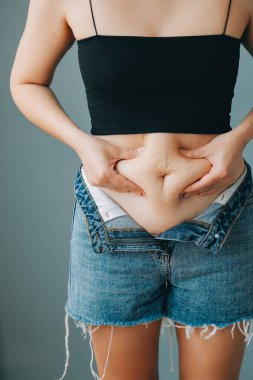 Şişman kadın, şişko, obez kadın el ele tutuşan ölçü bandıyla göbek yağı, kadın diyeti yaşam tarzı konsepti