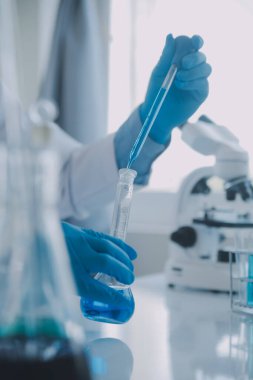 Coronavirus aşısı geliştirmek için mikroskop ile çalışan biyokimyasal araştırma ekibi farmasötik araştırma laboratuvarında, seçici odaklı
