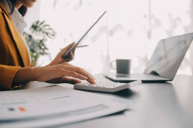 Bir ofis masası, vergi, rapor, muhasebe, istatistik ve analitik araştırma kavramında matematik finansmanı için hesap makinesi ve dizüstü bilgisayar kullanan Asyalı İş kadını