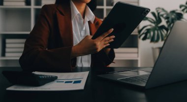 Bir ofis masası, vergi, rapor, muhasebe, istatistik ve analitik araştırma kavramında matematik finansmanı için hesap makinesi ve dizüstü bilgisayar kullanan Asyalı İş kadını