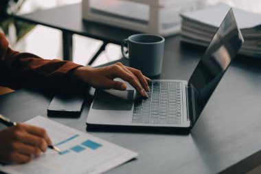 Bir ofis masası, vergi, rapor, muhasebe, istatistik ve analitik araştırma kavramında matematik finansmanı için hesap makinesi ve dizüstü bilgisayar kullanan Asyalı İş kadını