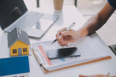 Emlakçı müşterilere örnek evler, ipotekli kredi sözleşmeleri veriyor. Kiralık bir ev alıp satmak için bir sözleşme yap. ve ev sigortası sözleşmeleri, ev kredisi konseptleri