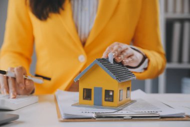 Emlakçı müşterilere örnek evler, ipotekli kredi sözleşmeleri veriyor. Kiralık bir ev alıp satmak için bir sözleşme yap. ve ev sigortası sözleşmeleri, ev kredisi konseptleri