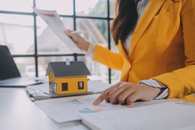 Emlakçı müşterilere örnek evler, ipotekli kredi sözleşmeleri veriyor. Kiralık bir ev alıp satmak için bir sözleşme yap. ve ev sigortası sözleşmeleri, ev kredisi konseptleri