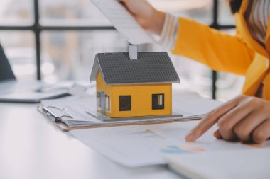 Emlakçı müşterilere örnek evler, ipotekli kredi sözleşmeleri veriyor. Kiralık bir ev alıp satmak için bir sözleşme yap. ve ev sigortası sözleşmeleri, ev kredisi konseptleri