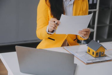 Emlakçı müşterilere örnek evler, ipotekli kredi sözleşmeleri veriyor. Kiralık bir ev alıp satmak için bir sözleşme yap. ve ev sigortası sözleşmeleri, ev kredisi konseptleri