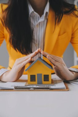 Emlakçı müşterilere örnek evler, ipotekli kredi sözleşmeleri veriyor. Kiralık bir ev alıp satmak için bir sözleşme yap. ve ev sigortası sözleşmeleri, ev kredisi konseptleri