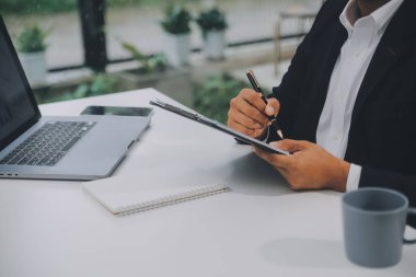 İş adamları ofiste toplanıp laptoplar, tablet planlama ve ofisteki meslektaşların beyin fırtınası stratejileri hakkında notlar yazıyorlar.