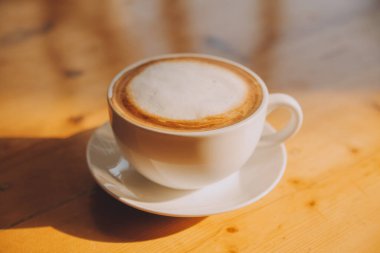 Tahta masada, beyaz fincanda kaşık ile kahve..