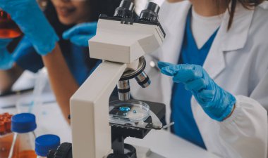 Coronavirus aşısı geliştirmek için mikroskop ile çalışan biyokimyasal araştırma ekibi farmasötik araştırma laboratuvarında, seçici odaklı