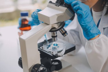 Coronavirus aşısı geliştirmek için mikroskop ile çalışan biyokimyasal araştırma ekibi farmasötik araştırma laboratuvarında, seçici odaklı