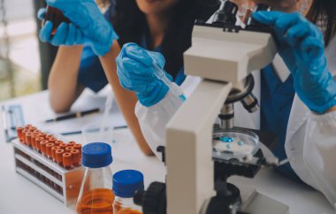 Coronavirus aşısı geliştirmek için mikroskop ile çalışan biyokimyasal araştırma ekibi farmasötik araştırma laboratuvarında, seçici odaklı