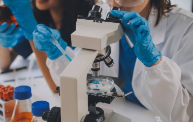 Coronavirus aşısı geliştirmek için mikroskop ile çalışan biyokimyasal araştırma ekibi farmasötik araştırma laboratuvarında, seçici odaklı