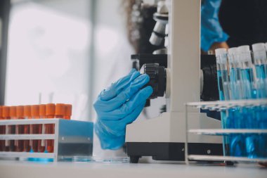 Coronavirus aşısı geliştirmek için mikroskop ile çalışan biyokimyasal araştırma ekibi farmasötik araştırma laboratuvarında, seçici odaklı