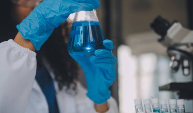 Coronavirus aşısı geliştirmek için mikroskop ile çalışan biyokimyasal araştırma ekibi farmasötik araştırma laboratuvarında, seçici odaklı