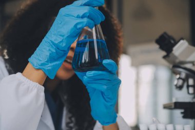 Coronavirus aşısı geliştirmek için mikroskop ile çalışan biyokimyasal araştırma ekibi farmasötik araştırma laboratuvarında, seçici odaklı