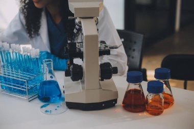 Coronavirus aşısı geliştirmek için mikroskop ile çalışan biyokimyasal araştırma ekibi farmasötik araştırma laboratuvarında, seçici odaklı