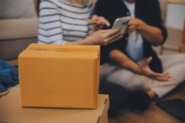 İki Asyalı blogcu, dükkanında canlı yayın yapan videoyu kaydetmek için kameranın önünde kıyafetlerini gösteriyor. Çevrimiçi alışveriş arabası fikri. Evdeki kanepede.