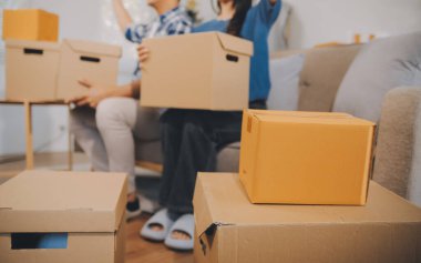 İki Asyalı blogcu, dükkanında canlı yayın yapan videoyu kaydetmek için kameranın önünde kıyafetlerini gösteriyor. Çevrimiçi alışveriş arabası fikri. Evdeki kanepede.