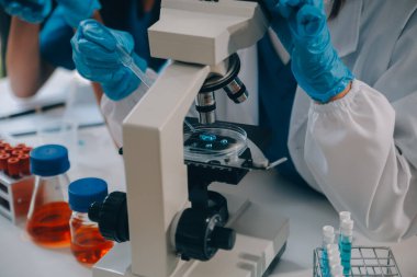 Coronavirus aşısı geliştirmek için mikroskop ile çalışan biyokimyasal araştırma ekibi farmasötik araştırma laboratuvarında, seçici odaklı