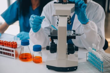 Coronavirus aşısı geliştirmek için mikroskop ile çalışan biyokimyasal araştırma ekibi farmasötik araştırma laboratuvarında, seçici odaklı