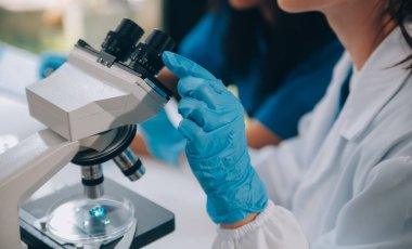 Coronavirus aşısı geliştirmek için mikroskop ile çalışan biyokimyasal araştırma ekibi farmasötik araştırma laboratuvarında, seçici odaklı