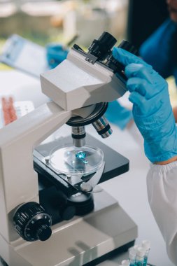 Coronavirus aşısı geliştirmek için mikroskop ile çalışan biyokimyasal araştırma ekibi farmasötik araştırma laboratuvarında, seçici odaklı