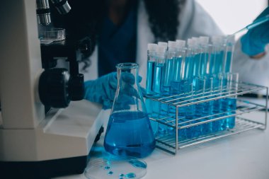 Coronavirus aşısı geliştirmek için mikroskop ile çalışan biyokimyasal araştırma ekibi farmasötik araştırma laboratuvarında, seçici odaklı