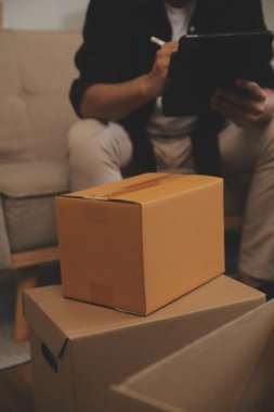 İki Asyalı blogcu, dükkanında canlı yayın yapan videoyu kaydetmek için kameranın önünde kıyafetlerini gösteriyor. Çevrimiçi alışveriş arabası fikri. Evdeki kanepede.