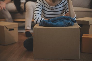 İki Asyalı blogcu, dükkanında canlı yayın yapan videoyu kaydetmek için kameranın önünde kıyafetlerini gösteriyor. Çevrimiçi alışveriş arabası fikri. Evdeki kanepede.