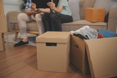 İki Asyalı blogcu, dükkanında canlı yayın yapan videoyu kaydetmek için kameranın önünde kıyafetlerini gösteriyor. Çevrimiçi alışveriş arabası fikri. Evdeki kanepede.