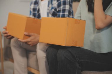 İki Asyalı blogcu, dükkanında canlı yayın yapan videoyu kaydetmek için kameranın önünde kıyafetlerini gösteriyor. Çevrimiçi alışveriş arabası fikri. Evdeki kanepede.